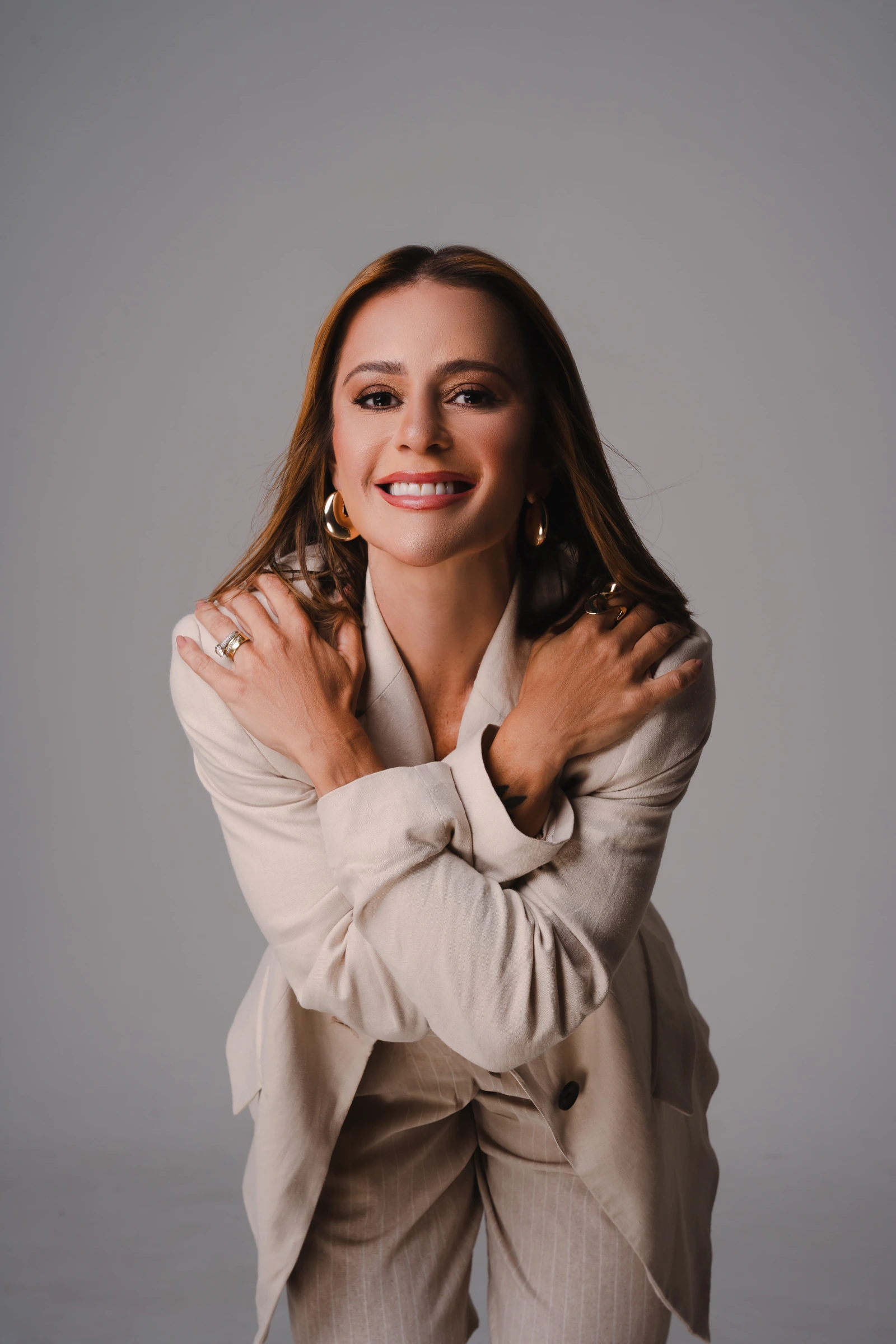 Dra. Karina Cobucci sorrindo, com os braços cruzados sobre os ombros